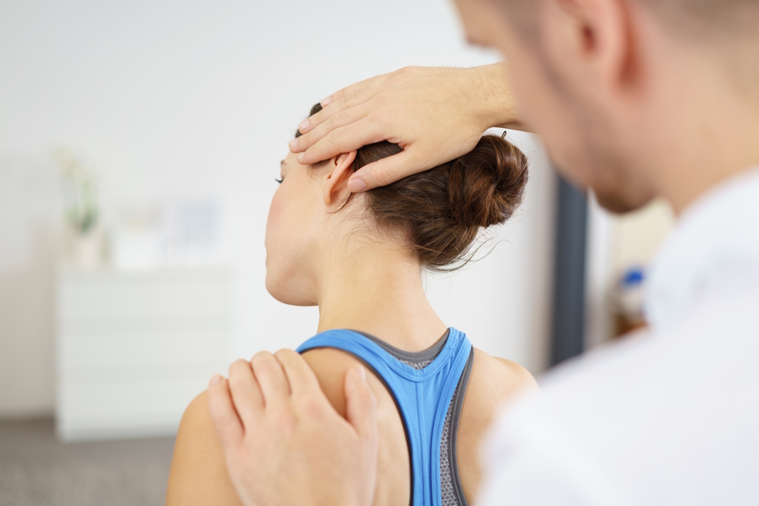 Ein Orthopäde behandelt den Nacken einer Patientin.